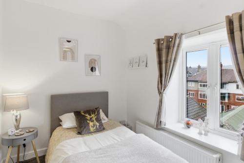 a bedroom with a bed and a window at Cannons Loft Central Buxton, Duplex loft 3 bedroom Set over 3 floors stairs no lift sleeps 5 in Buxton