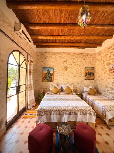 a bedroom with two beds with red chairs in it at Riad Titima Essaouira in Essaouira