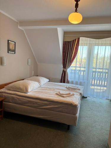 a bedroom with a large bed with a window at Hotelik Zełwągi in Mikołajki
