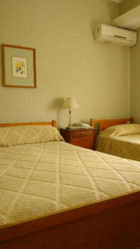 a bedroom with two beds and a night stand with a fan at Hotel Ro Che Hil Tandil in Tandil