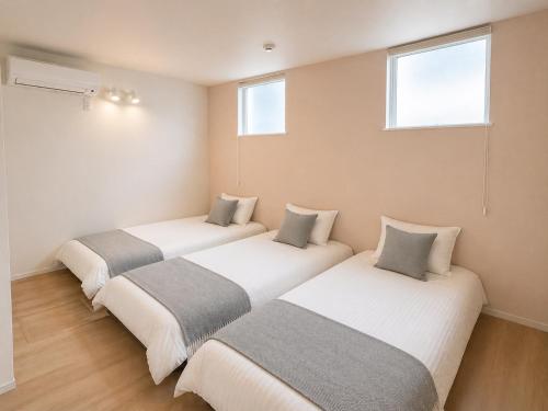 three beds are lined up in a room at 北鎌倉駅徒歩圏 観光便利 最大7名 2寝室 広々滞在 101 in Kamakura
