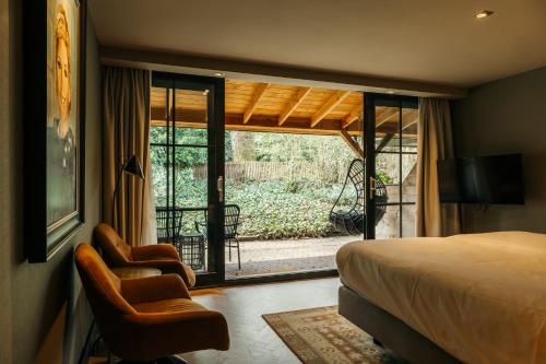 a bedroom with a bed and two chairs and a balcony at Van der Valk Hotel Apeldoorn - de Cantharel in Apeldoorn