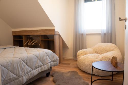 a bedroom with a bed and a chair and a window at Ferienwohnung Lindelskopf in Ludwigswinkel