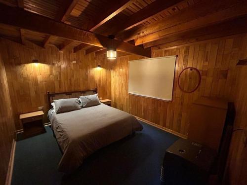 a bedroom with a bed and a projection screen at Rayen Mahuida - Las Trancas in Las Trancas