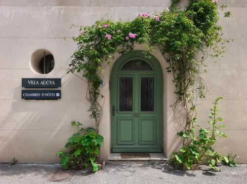 a green door on a building with flowers above it at VILLA ADOYA Chambre d'hôtes Aigues-Mortes intra muros au calme climatisation réversible PISCINE WIFI ascenseur PARKING gratuit in Aigues-Mortes
