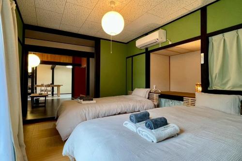 two beds in a room with green walls at あざみ庵 奄美大島 in Amami