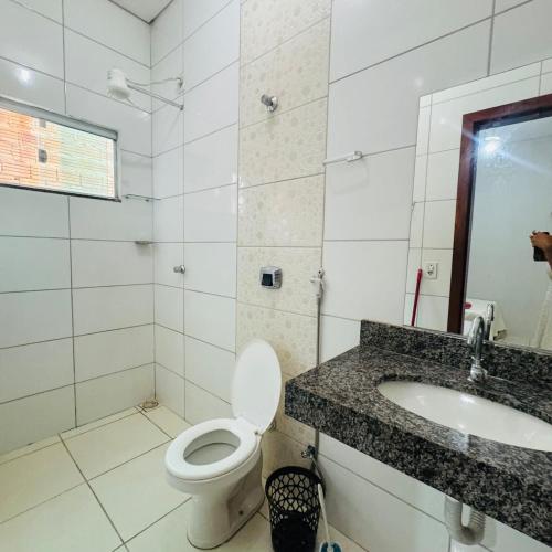 a white bathroom with a toilet and a sink at casa mobiliada em gurupi in Gurupi