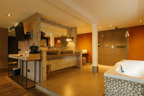 a bathroom with a tub and a sink and a mirror at Van der Valk Hotel Apeldoorn - de Cantharel in Apeldoorn
