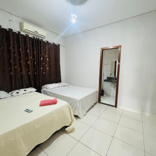 a room with two beds and a mirror in it at casa mobiliada em gurupi in Gurupi