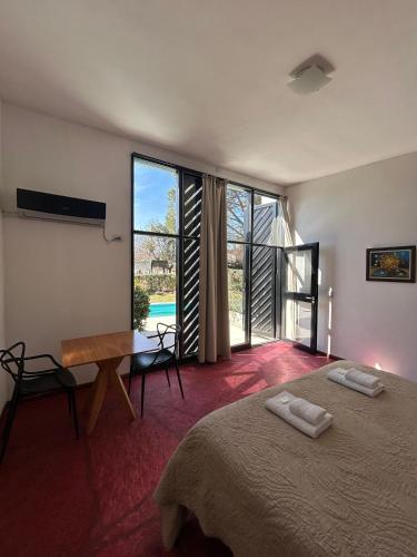 a bedroom with a bed and a desk and a window at Las Artes Lodge in Mina Clavero