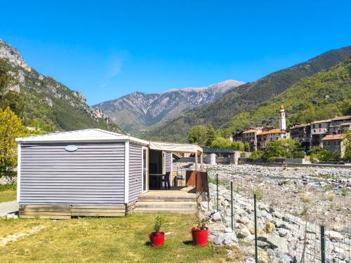 a small house in a field with mountains in the background at Camping 3* Les Templiers in Roquebillière