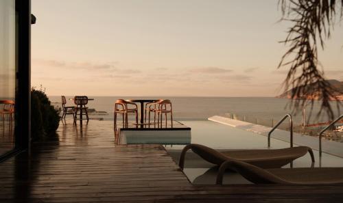a table and chairs on a boardwalk next to the ocean at Aguas de Ibiza by NCalma Hotels in Santa Eularia des Riu