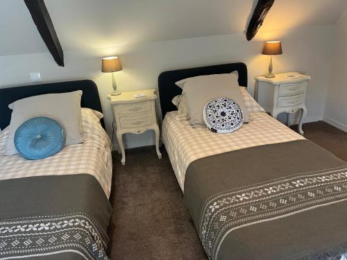 a bedroom with two beds and two night stands at L'Ancienne Boulangerie in Collinée