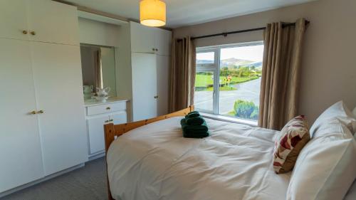 a bedroom with a bed and a large window at Greenway Riverside House - Cahersiveen in Foilmore Bridge