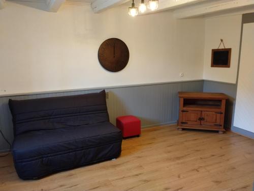 a living room with a couch and a clock on the wall at Maison de charme a moye in Moye
