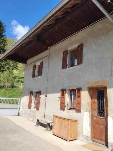 a building with wooden shuttered windows and a bench at Maison de charme a moye in Moye
