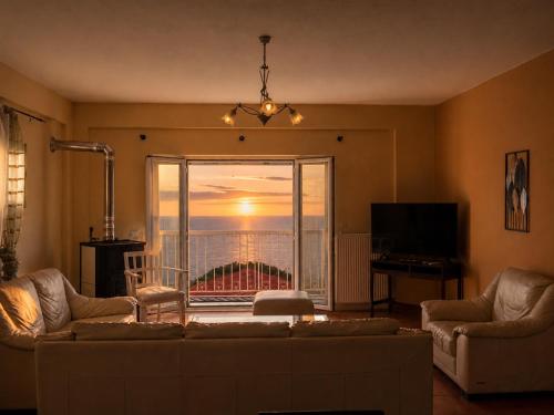 a living room with a couch and a view of the ocean at Sunset apartment by the sea in Palaiochórion