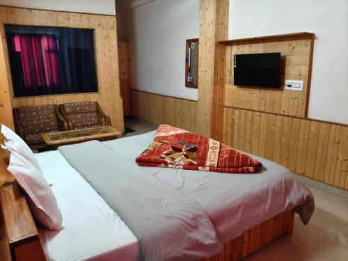 a bedroom with a bed with a pillow and a television at Chander Guest House in Kasol