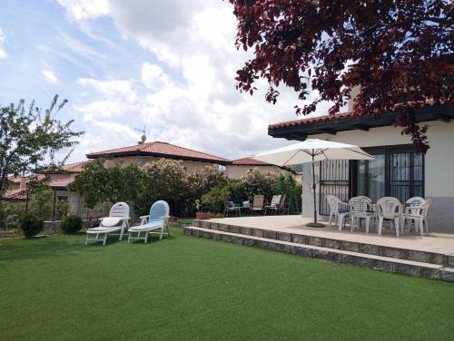 a group of chairs and an umbrella on a lawn at Chalet independiente con vistas in Bustarviejo