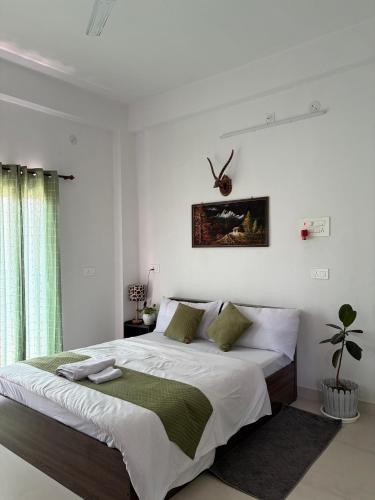 a white bedroom with a large bed and a window at The Cozy Petals in Gaya