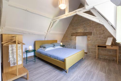 a bedroom with a bed and a stone wall at Camping and Gîtes - Le Mas d'Ayen in Ayen