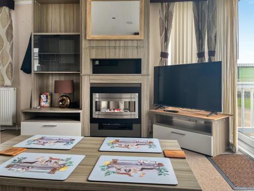a living room with a table with a tv and a fireplace at Pebbles in Pakefield