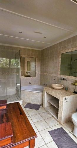 a bathroom with a tub and a sink and a toilet at Daniel's Sunset Garden in Richards Bay