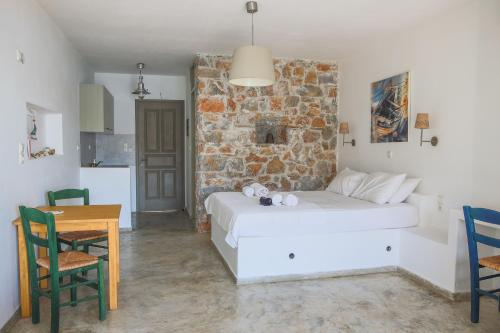 a bedroom with a white bed and a stone wall at Dimitra Studios in Aegiali