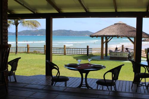 a table and chairs on a deck with a view of the beach at Hotel Atalaia do Mariscal in Bombinhas