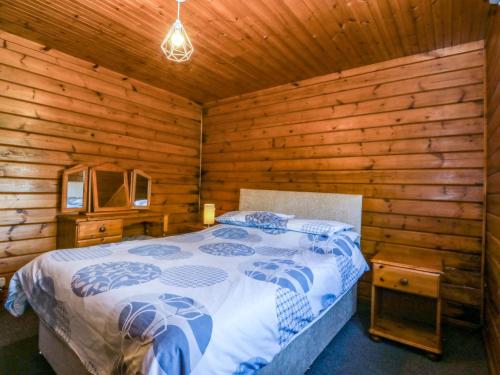a bedroom with a bed in a log cabin at Lodge 4 - Bron Eifion in Criccieth