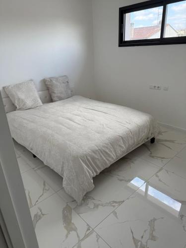 a bed in a white room with a window at Villa avec piscine jacuzzi et sauna in Saint-André-de-Cubzac