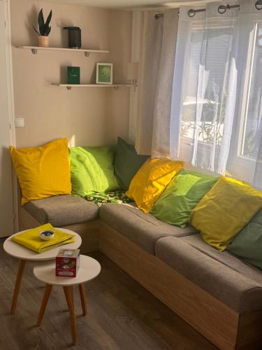 a couch with yellow and green pillows in a room at Escale Sud in Canet-en-Roussillon