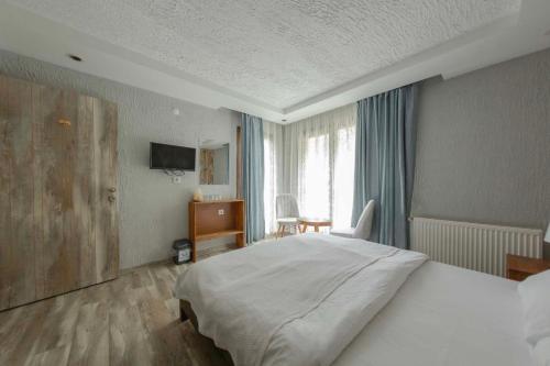 a bedroom with a bed and a desk and a television at Elikti Otel in Ardeşen