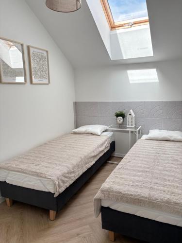 two beds in a white room with two windows at Dobre Miejsce in Skoczów