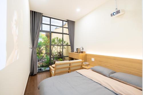 a bedroom with a bed and a large window at Cái Vườn Ấm in Lái Thiêu