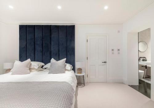 a white bedroom with a large bed and a bathroom at 3 Bedroom, 3 bathroom large flat with sea views! in Hastings