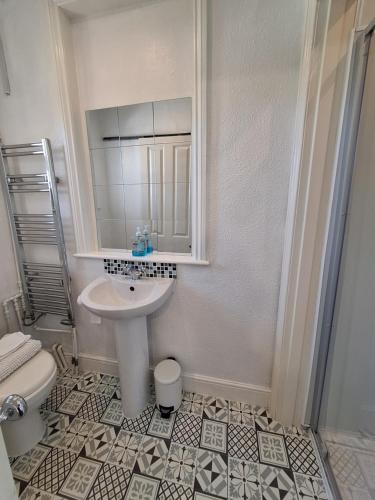 a white bathroom with a sink and a toilet at The Studio Apartment in Weymouth