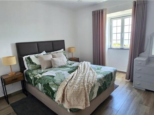 a bedroom with a bed with a green blanket on it at Lucy's Rosegarden in Urzelina