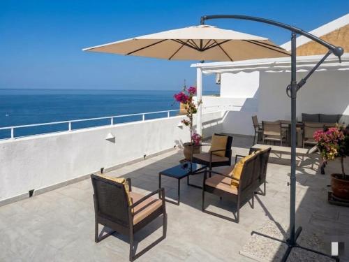 a patio with chairs and an umbrella and the ocean at Sagittarius B&B in Cetraro