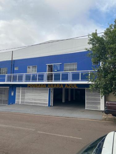 a blue building with a garage with a sign on it at Hotel Arara Azul in Barra do Garças