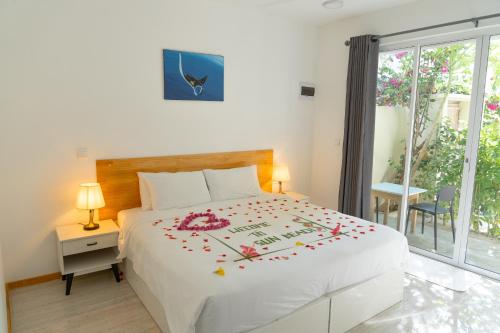 a bedroom with a white bed with flowers on it at Sun Beach Dhigurah in Dhigurah