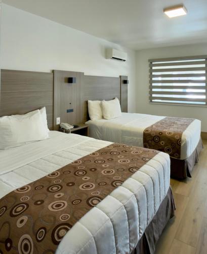 a hotel room with two beds and a window at Spring Water Hotel & Suites in Cuauhtémoc