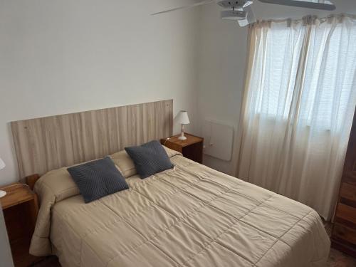 a bedroom with a bed with two blue pillows at Mageeva Miramar Bs As Argentina Departamentos in Miramar