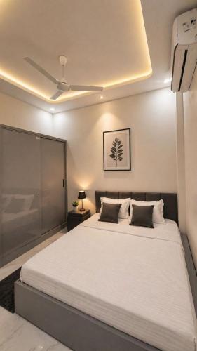 a bedroom with a large white bed with a ceiling at Lado by Stay Junction in Indore