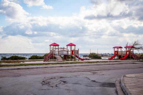 a playground on the side of a street with the water at Sea View Apartments near Athens Airport in Artemida