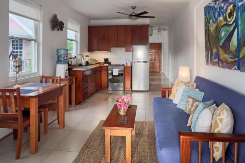 a living room and kitchen with a blue couch and a table at Weezie's Ocean Front Hotel and Garden Cottages in Caye Caulker