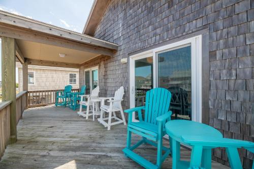 a deck with blue chairs and tables and windows at Seagrove View - NH MP 10.5, Oceanside, 800 ft to the BEACH, YMCA Passes in Nags Head