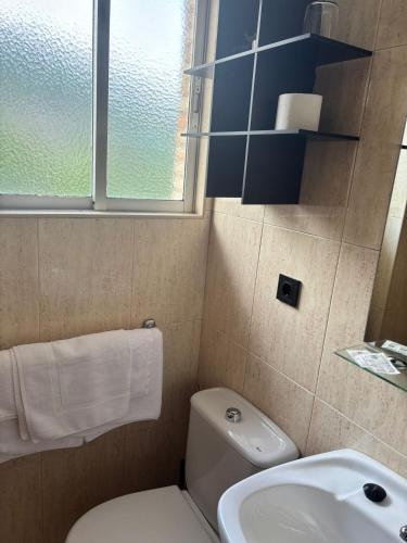 ein Badezimmer mit Toilette, Waschbecken und Fenster in der Unterkunft Hostal Baviera in Pesués