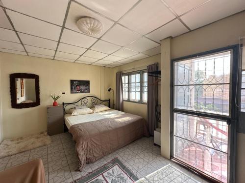 a bedroom with a bed and a large window at The Station Hostel in Sathani Ayutthaya