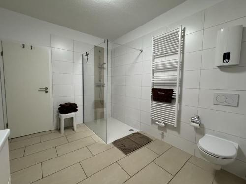 a white bathroom with a shower and a toilet at Mariehus in Wangerooge